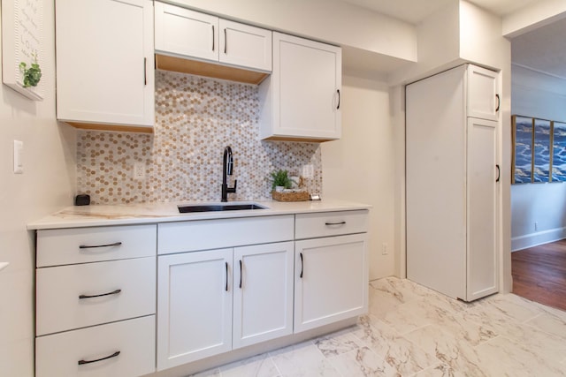 kitchen with decorative backsplash, white cabinets, light hardwood / wood-style flooring, and sink