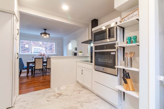 kitchen featuring white cabinets, appliances with stainless steel finishes, light wood-type flooring, and kitchen peninsula