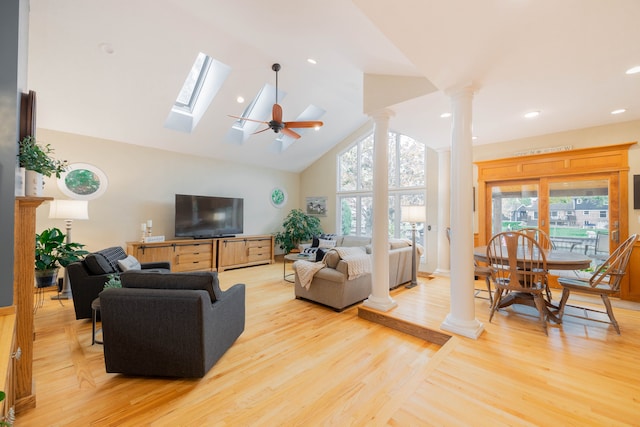 living room with light hardwood / wood-style floors, high vaulted ceiling, ceiling fan, and decorative columns