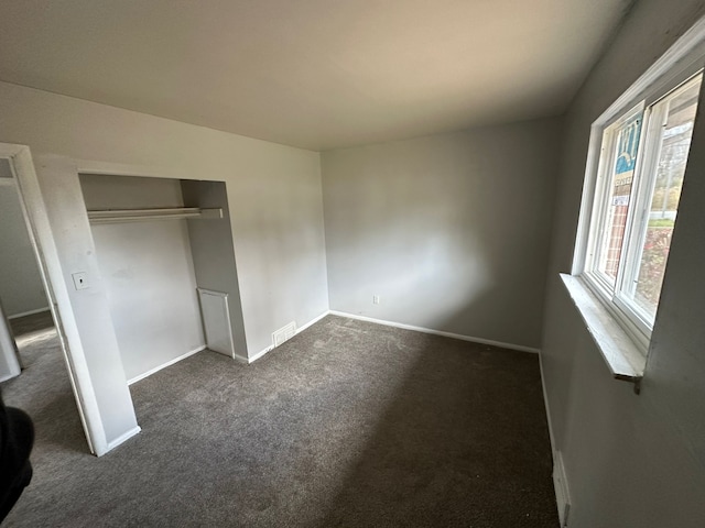 unfurnished bedroom with a closet and dark carpet