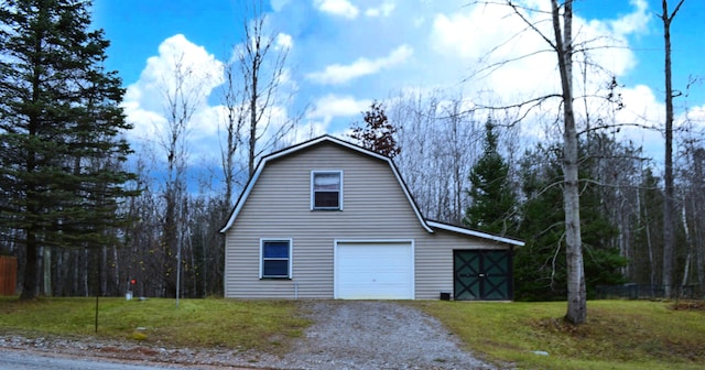 view of side of home featuring a garage, an outdoor structure, and a lawn