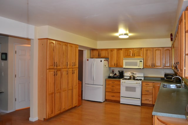 kitchen with light wood-type flooring, white appliances, and sink