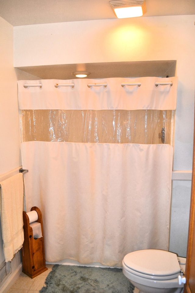 bathroom with curtained shower, tile patterned flooring, and toilet