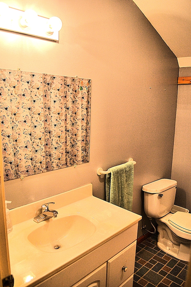 bathroom featuring tile patterned flooring, vanity, toilet, and lofted ceiling