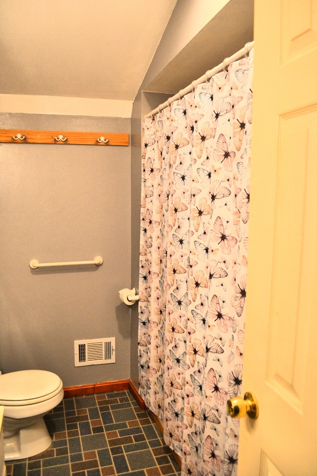 bathroom with lofted ceiling and toilet