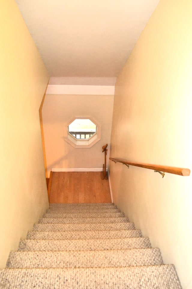 staircase featuring wood-type flooring and vaulted ceiling