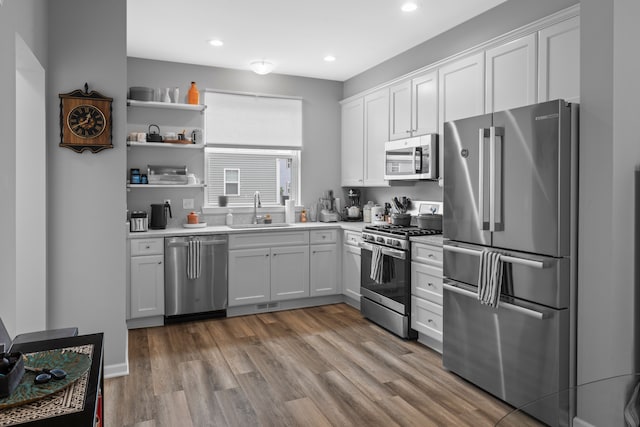 kitchen featuring white cabinetry, sink, light hardwood / wood-style flooring, and appliances with stainless steel finishes