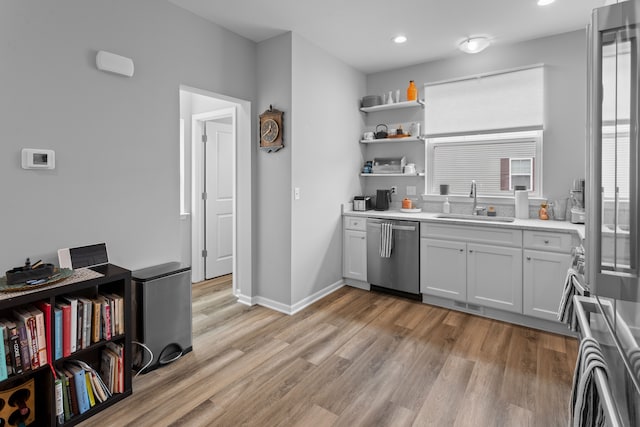 kitchen with stainless steel dishwasher, white cabinets, light wood-type flooring, and sink