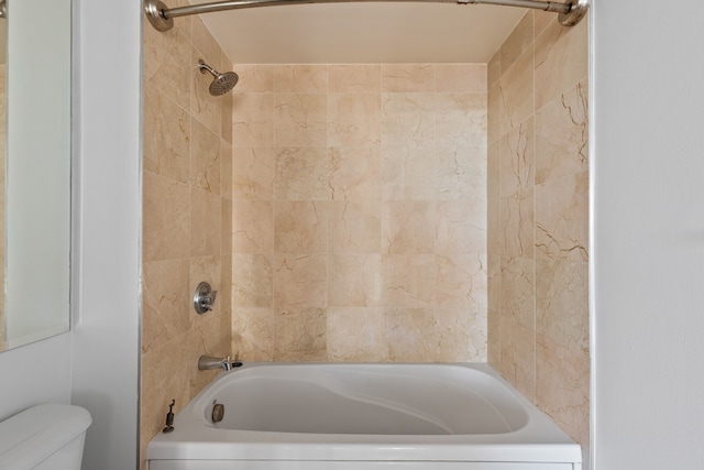 bathroom featuring tiled shower / bath combo and toilet