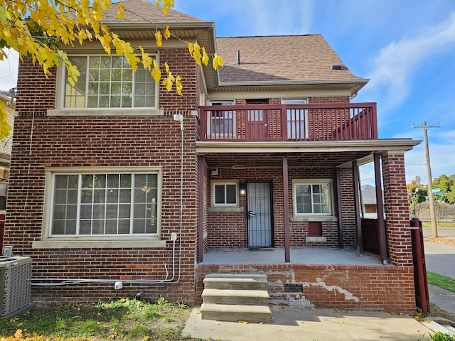 view of front of property with central air condition unit, a balcony, and covered porch