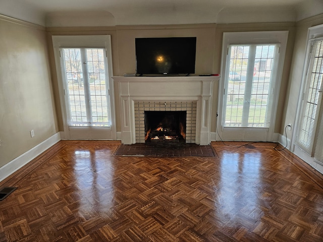 unfurnished living room featuring dark parquet flooring and a brick fireplace