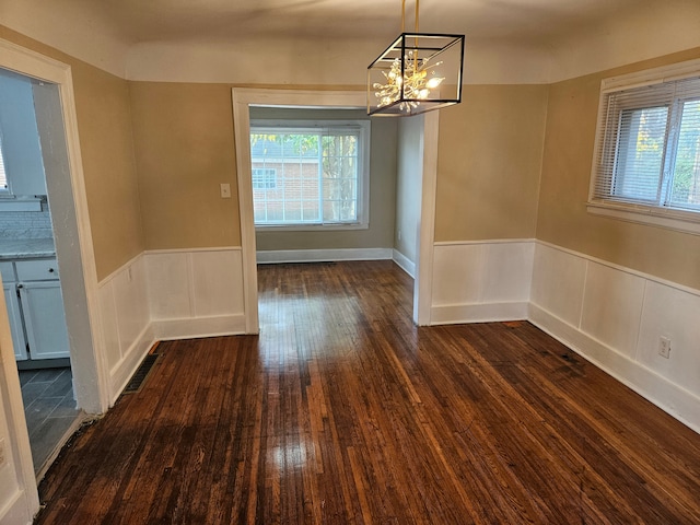 unfurnished dining area with dark hardwood / wood-style flooring and a notable chandelier