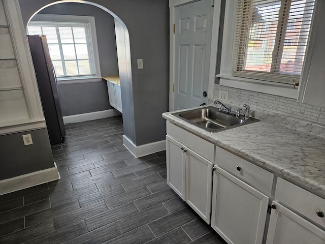 kitchen with backsplash, a wealth of natural light, sink, and white cabinets