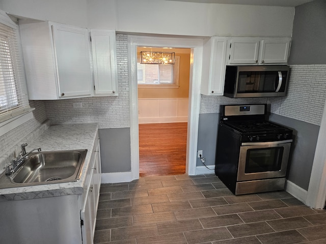 kitchen featuring dark wood-type flooring, sink, appliances with stainless steel finishes, tasteful backsplash, and white cabinetry