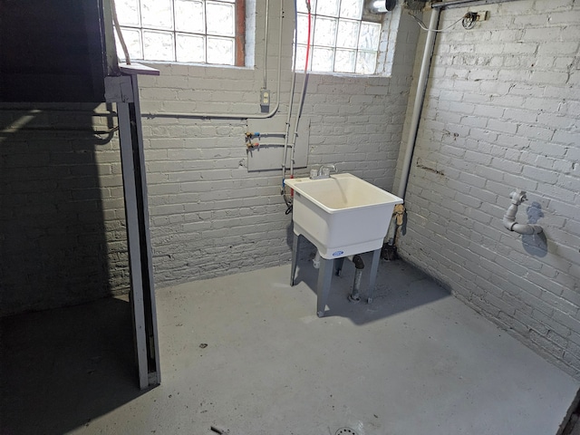 basement featuring sink and brick wall