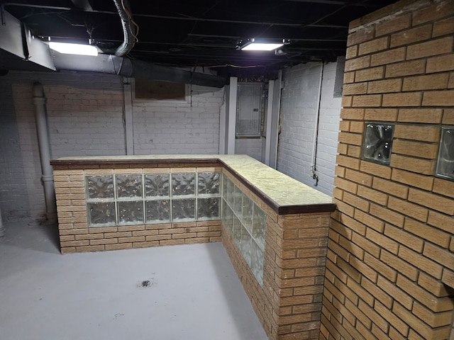 basement with electric panel and brick wall