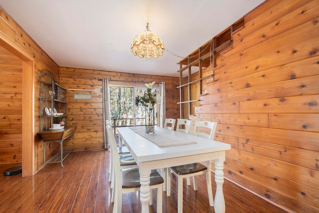 dining area with wooden walls and dark wood-type flooring