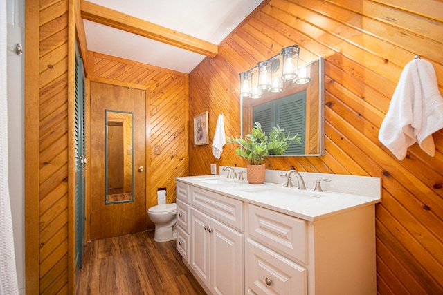 bathroom with hardwood / wood-style floors, vanity, wooden walls, vaulted ceiling with beams, and toilet