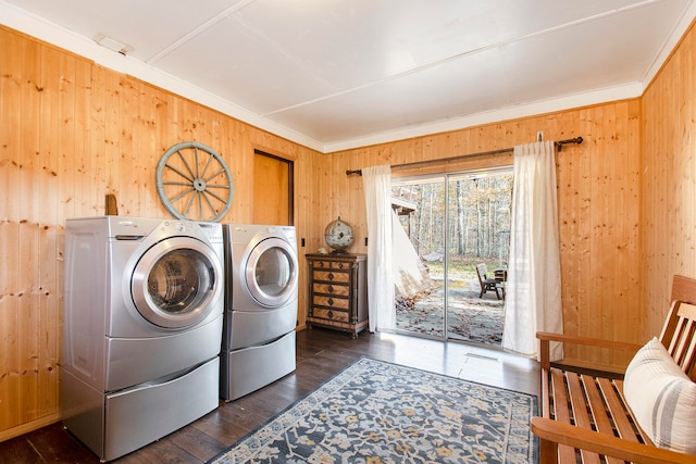 laundry area featuring dark hardwood / wood-style floors, crown molding, wooden walls, and washing machine and clothes dryer