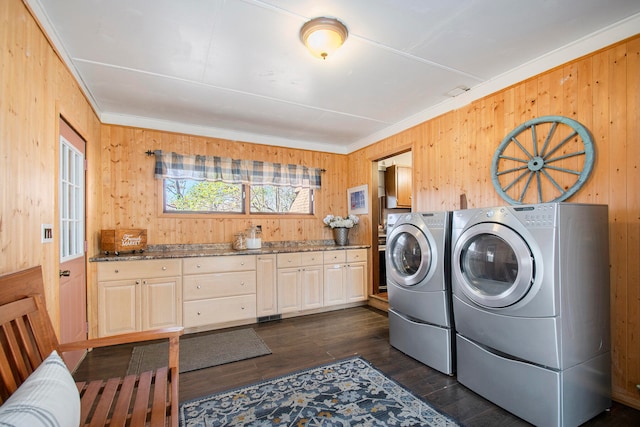 washroom featuring ornamental molding, washer and clothes dryer, dark wood-type flooring, and wood walls