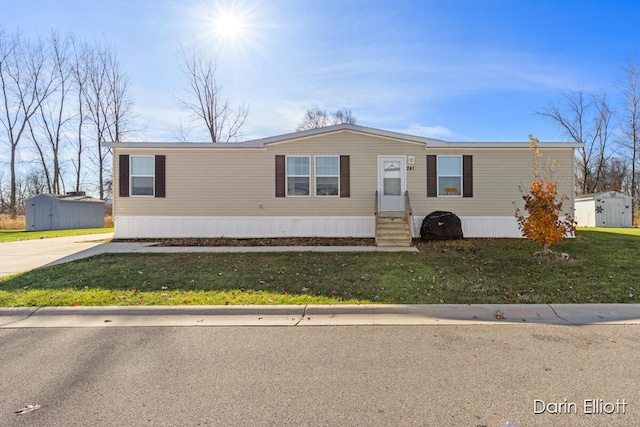 manufactured / mobile home featuring a front lawn and an outdoor structure