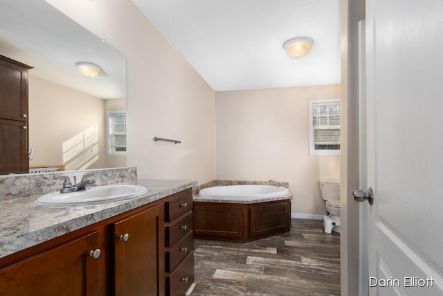 bathroom featuring a washtub, wood-type flooring, vanity, and toilet