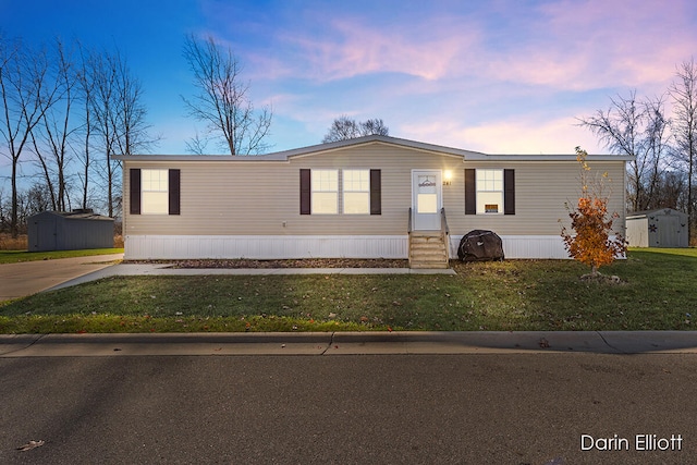 manufactured / mobile home featuring a yard and a storage shed