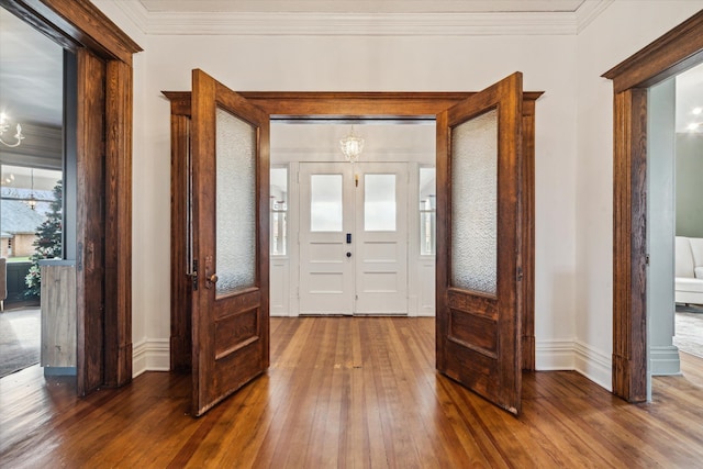 entrance foyer with hardwood / wood-style flooring, ornamental molding, french doors, and an inviting chandelier