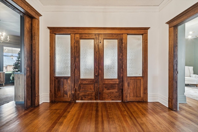 interior space featuring dark hardwood / wood-style flooring, french doors, ornamental molding, and an inviting chandelier