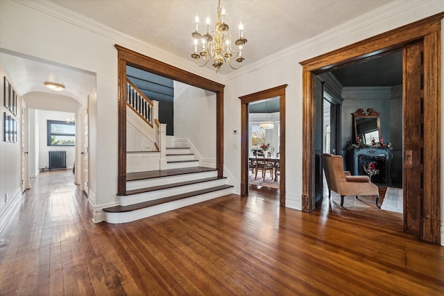 interior space with radiator, ornamental molding, a textured ceiling, hardwood / wood-style flooring, and an inviting chandelier