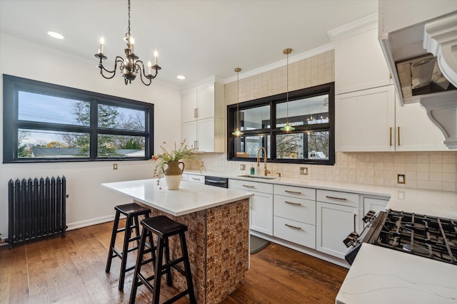 kitchen with dark wood-type flooring, sink, radiator heating unit, white cabinetry, and hanging light fixtures