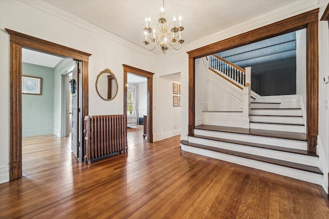 interior space with ornamental molding, a textured ceiling, an inviting chandelier, hardwood / wood-style floors, and radiator heating unit