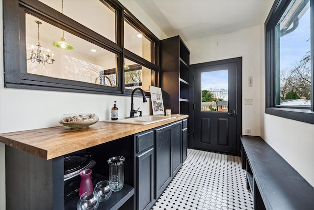 bar featuring butcher block countertops, hanging light fixtures, a healthy amount of sunlight, and sink