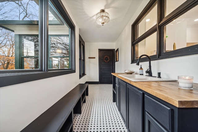 bar featuring butcher block counters, sink, and an inviting chandelier