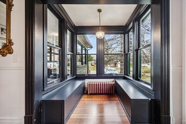 unfurnished sunroom featuring radiator heating unit and a notable chandelier