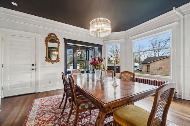 dining area with hardwood / wood-style floors, a notable chandelier, crown molding, and radiator