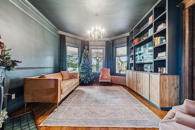 living area featuring hardwood / wood-style flooring, crown molding, radiator, and an inviting chandelier