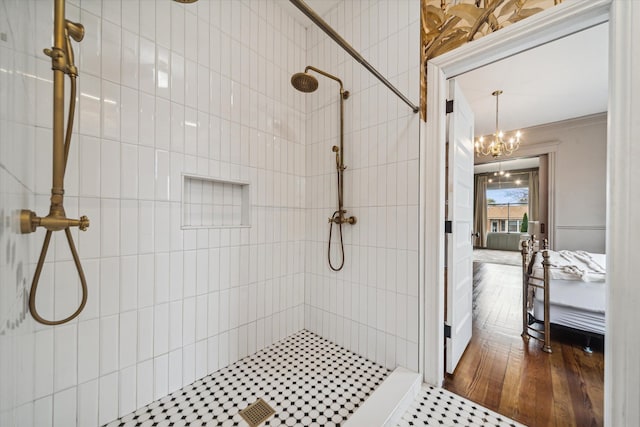 bathroom featuring hardwood / wood-style floors, crown molding, tiled shower, and a chandelier