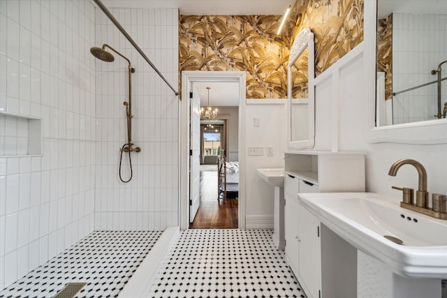 bathroom featuring double sink and tiled shower