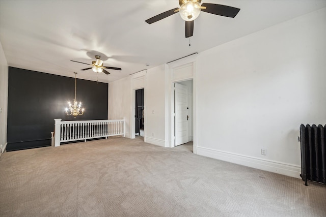 carpeted spare room featuring ceiling fan with notable chandelier and radiator heating unit