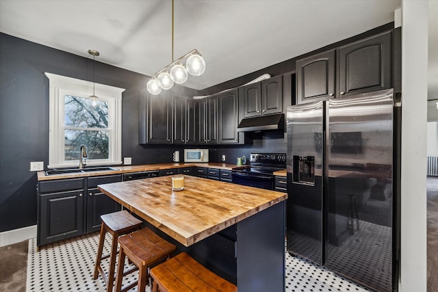 kitchen featuring a kitchen bar, stainless steel appliances, sink, a kitchen island, and butcher block counters