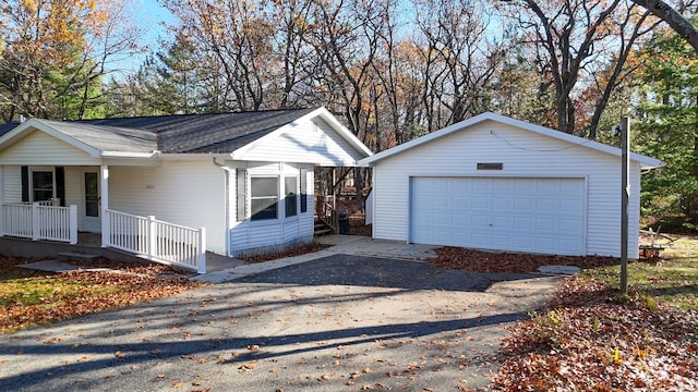 ranch-style house with a porch, a garage, and an outbuilding