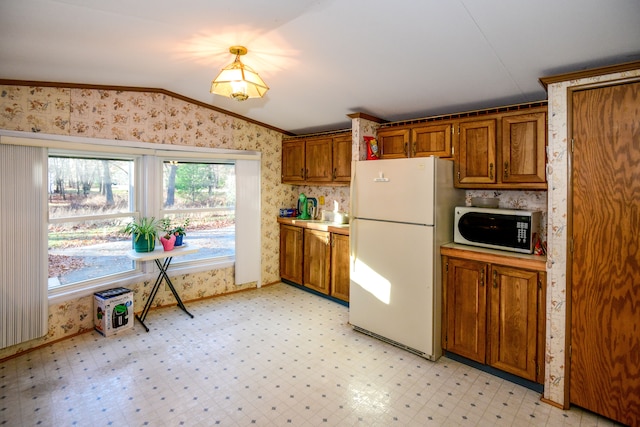 kitchen featuring lofted ceiling, white appliances, and ornamental molding