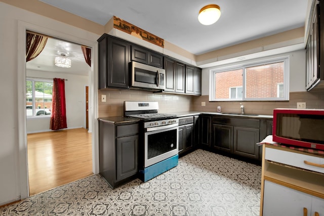 kitchen with decorative backsplash, sink, stainless steel appliances, and light hardwood / wood-style flooring