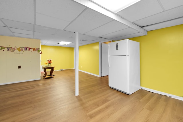 basement with a drop ceiling, white fridge, and wood-type flooring