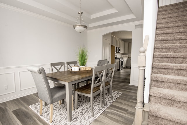 dining space featuring a raised ceiling, crown molding, and dark hardwood / wood-style flooring