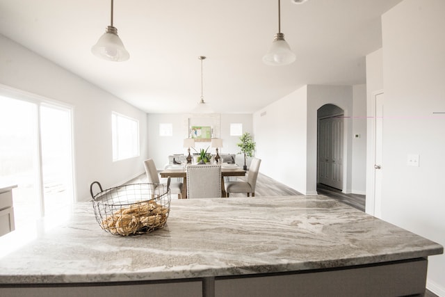 kitchen featuring light stone counters, hanging light fixtures, and wood-type flooring