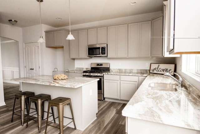 kitchen with sink, a center island, dark hardwood / wood-style flooring, decorative light fixtures, and appliances with stainless steel finishes