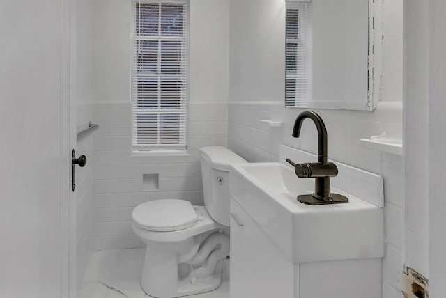 bathroom with vanity, tile walls, and toilet