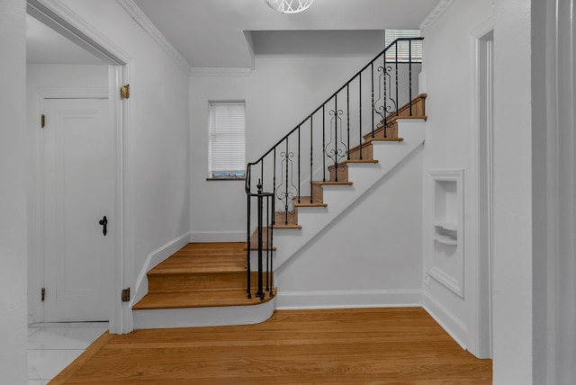 stairs featuring crown molding and hardwood / wood-style flooring